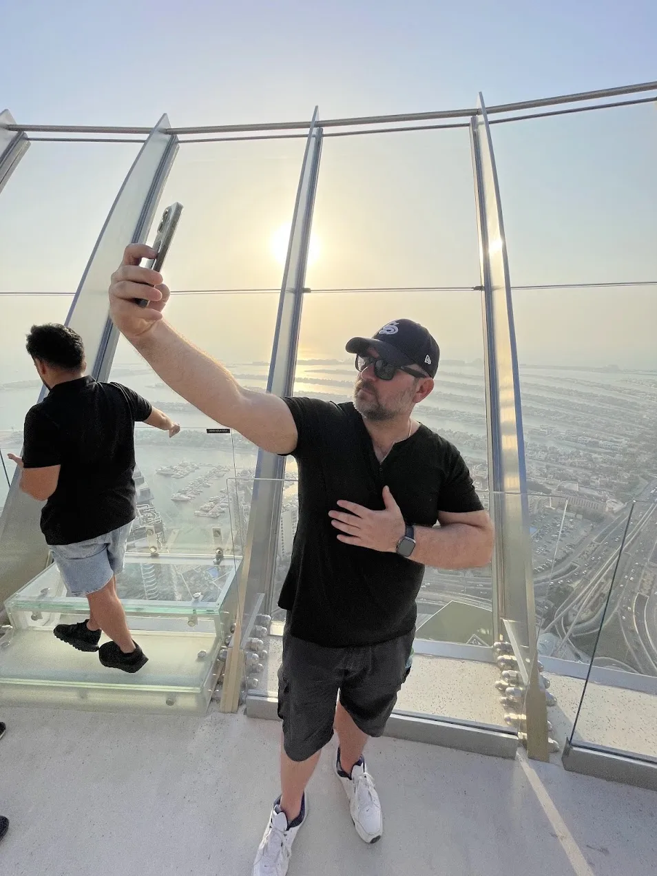 Sandro macht ein Selfie auf der Aussichtsplattform The View at The Palm, hinter der Glasbrüstung liegt bei tiefstehender Sonne die Palme Jumeirah